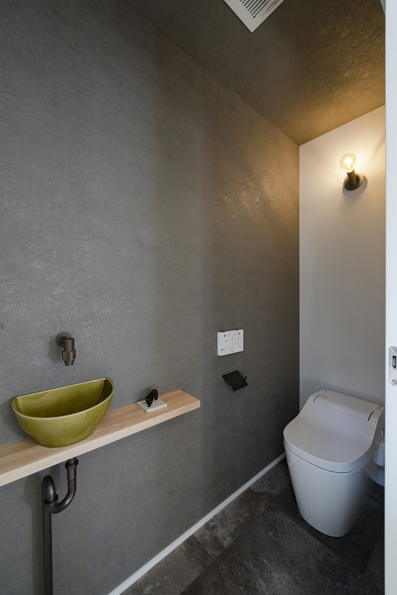 シンプルでシックにデザインされた1階のトイレ。手洗いカウンター付き