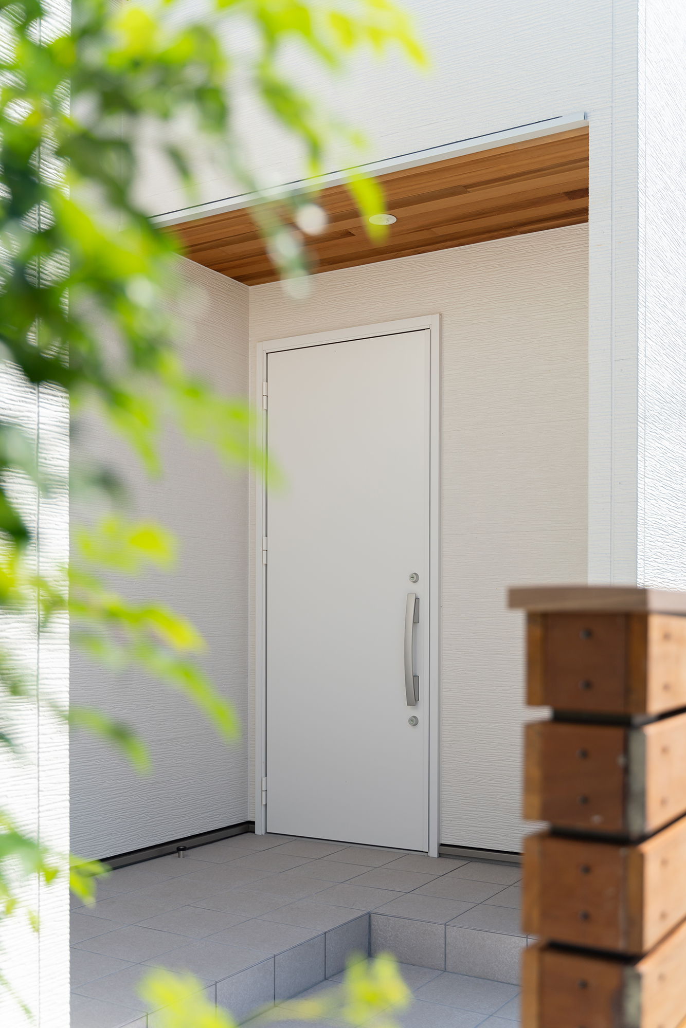 余計な装飾を施さず、白と木目でまとめたシンプルな玄関周り。軒に貼られたレッドシダーは室内側へと連続