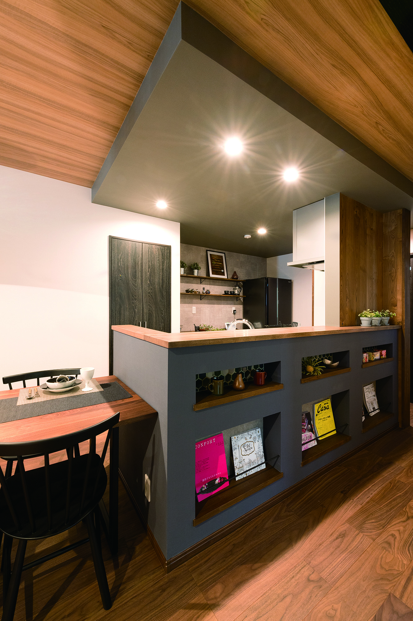 カフェ空間をイメージしたカウンター付きのオープンキッチン。カウンターを一段上げて、料理をしている手元を隠しつつ、飾り棚の空間を確保。