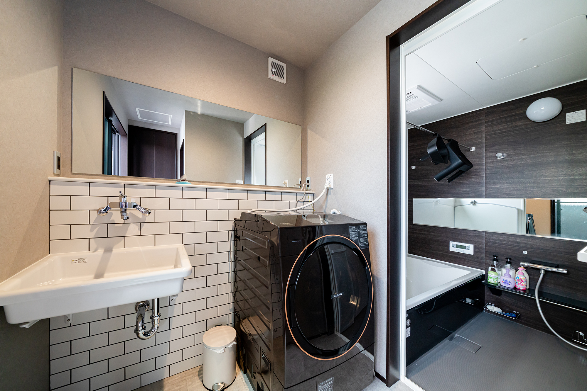 サブウェイタイルと一面の鏡が印象的なモノトーンでまとめた洗面＆浴室