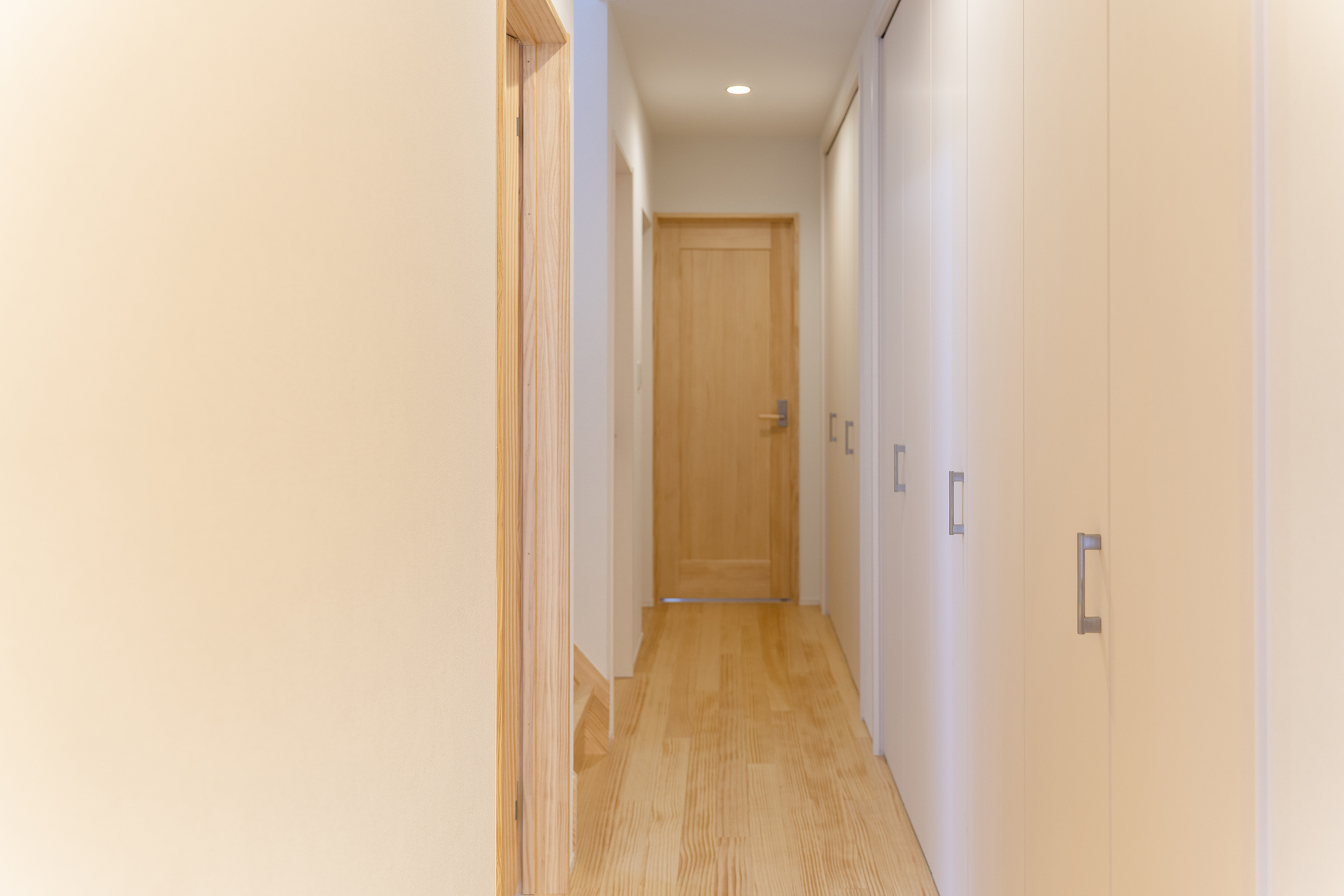 玄関から続く、廊下を兼ねた収納スペース。コート類など外出時に使うものをしまうのに便利。壁と同系色の扉を付けてすっきりと見せている