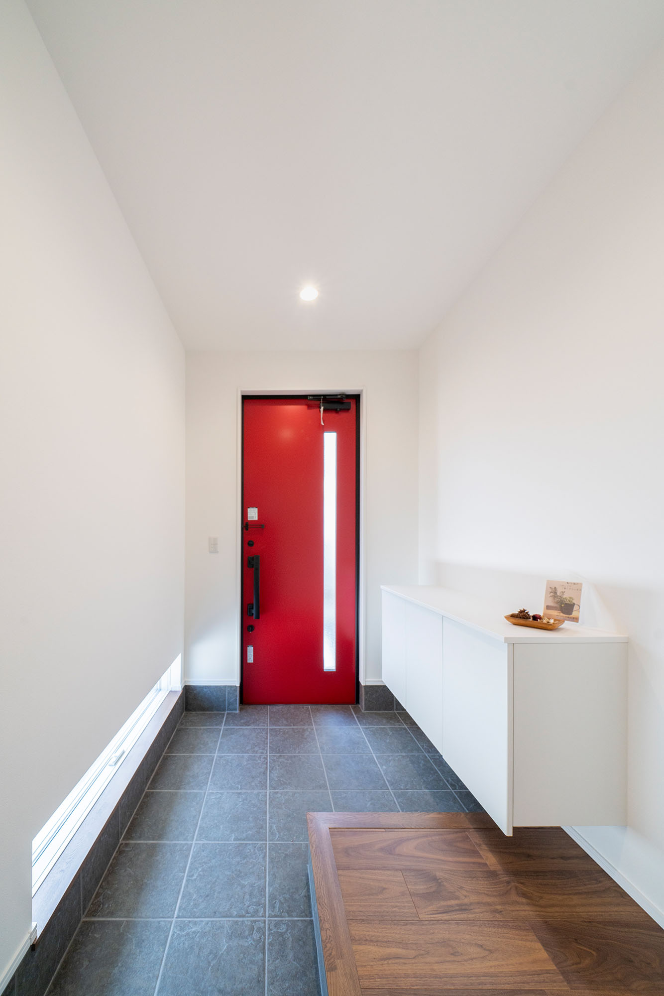 白と木を基調としたシンプルな空間に、赤い玄関ドアが映える